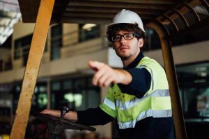 A forklift driver points to a dangerous situation report form pinned on the safety board. Learn more about mobile reporting dangerous situations at 1stReporting.com.