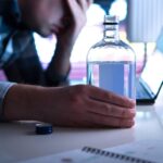 An employee sits at his desk with a bottle of alcohol. Using a employee reasonable suspicion observation checklist helps document these cringe-worthy events.