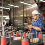 A factory worker reads quality assurance audits tips on a mobile device.