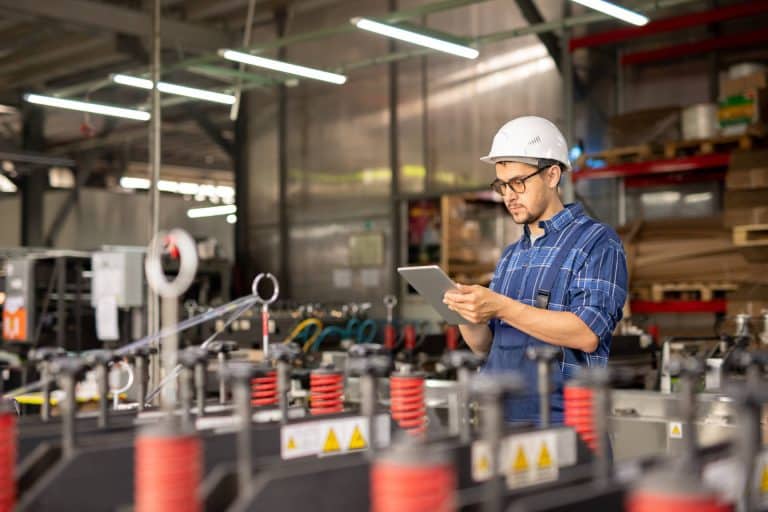 A factory worker reads quality assurance audits tips on a mobile device.