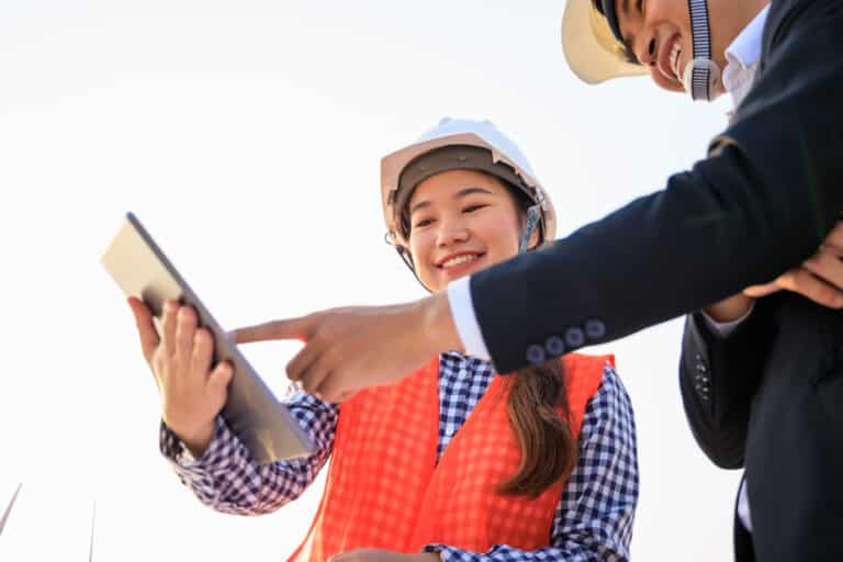 A worker and manager discuss a standard operating procedure template on a tablet mobile device