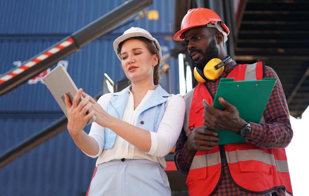 A manager shows a worker the new digital SOP template on a tablet running the 1st Reporting app.