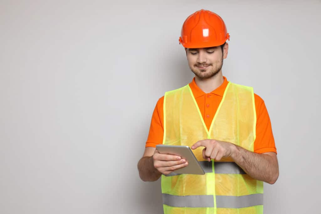 A worker happily prioritizes inspection efficiency by using the 1st Reporting application on a mobile tablet.