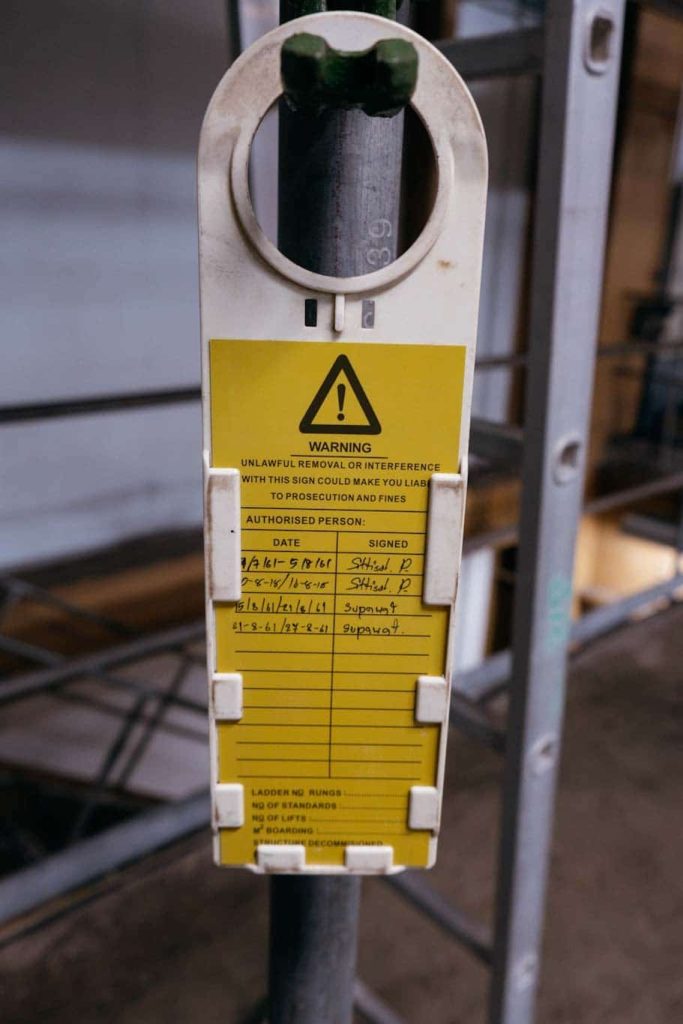 An orange inspction tag is attached to a vertical scaffold pipe in this work site photo.