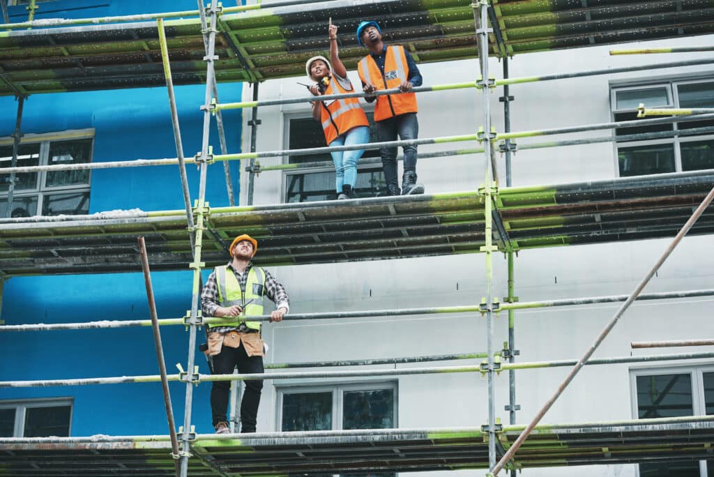 Workers stand on scaffolding