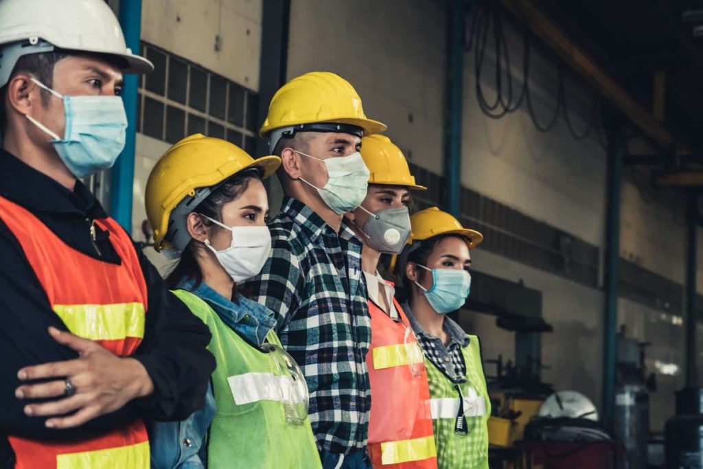 A group of workers proudly displays their use of personal protective equipment.