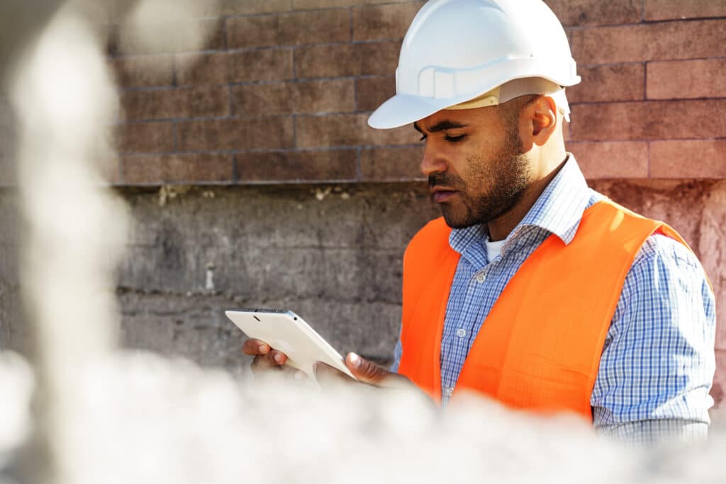 A construction worker uses a mobile reporting application for safety inspections.