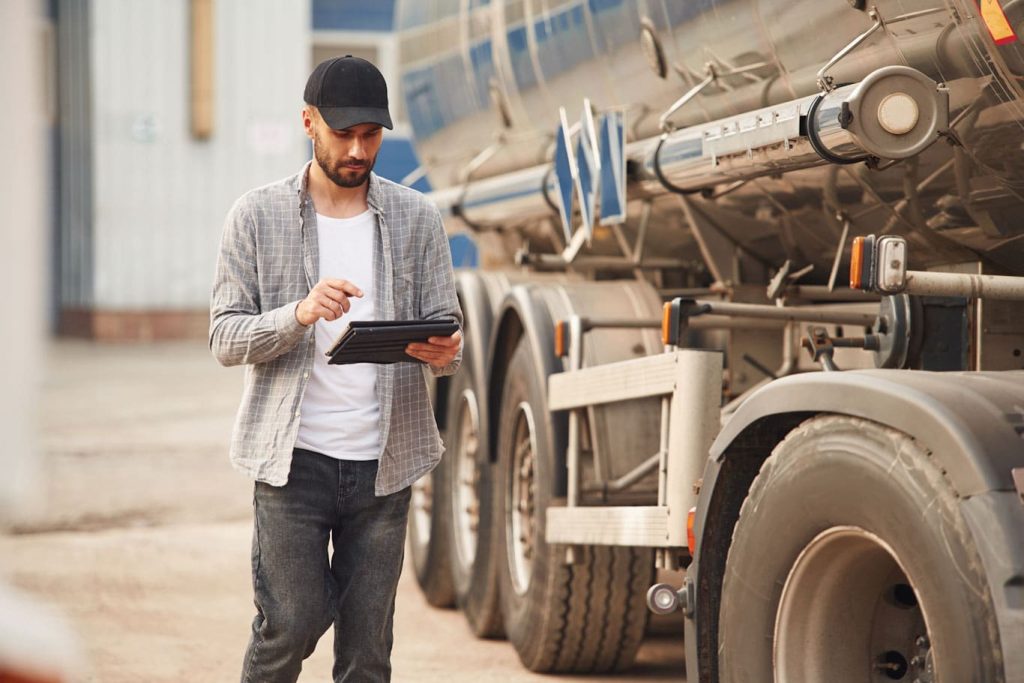 A truck driver using a tablet to complete his vehicle inspection report writing. Learn more about mobile reporting for fleet management at 1stReporting.com.