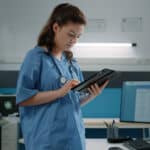 A healthcare worker uses a mobile tablet to complete a SOAP note template.