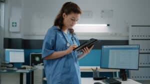 A healthcare worker uses a mobile tablet to complete a SOAP note template.