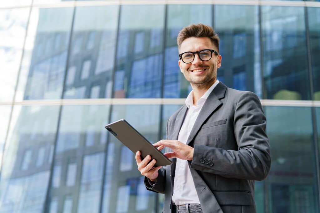 A male realtor happily uses his tablet with a real estate listing checklist running on the 1st Reporting app.