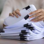 A person tries to organize a large stack of different types of incident reports.