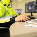 A security guard uses security incident reporting software on a desktop computer.
