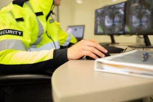 A security guard uses security incident reporting software on a desktop computer.