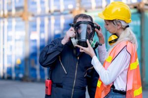 A safety manager helps a team member with a respirator after using the Respirator Inspection Checklist by 1stReporting.com.