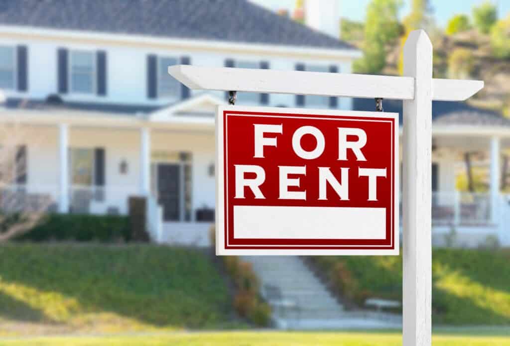 A large house with a rental sign out front.