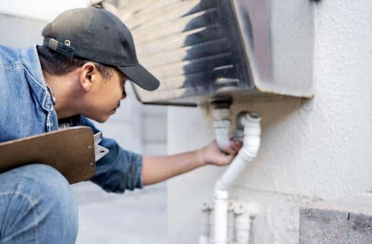 Maintenance person checks plumbing using the 1st Reporting Building Maintenance Checklist.
