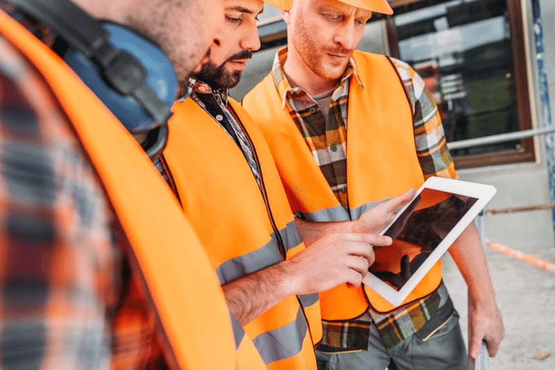 Construction safety officers review a mobile compliance reporting document on a tablet. Learn about mobile compliance reporting at 1stReporting.com.