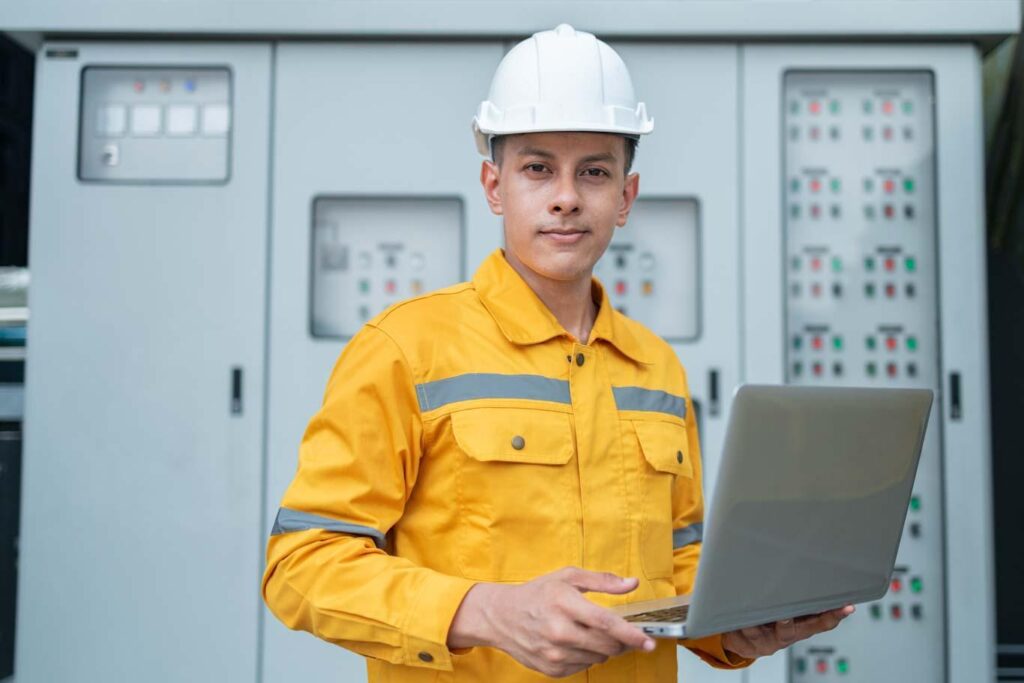 An electrical engineer uses a mobile laptop to complete a utilities compliance report. Learn more about field reporting in the utilities sector at 1stReporting.com.