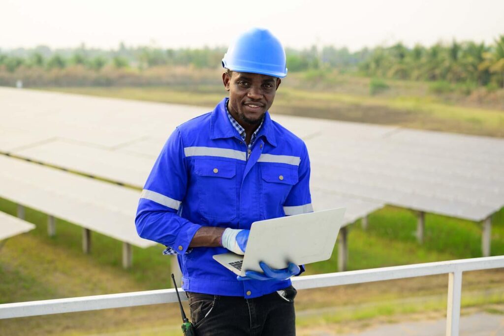 An engineer at a solar farm uses a laptop with a digital reporting tool installed.