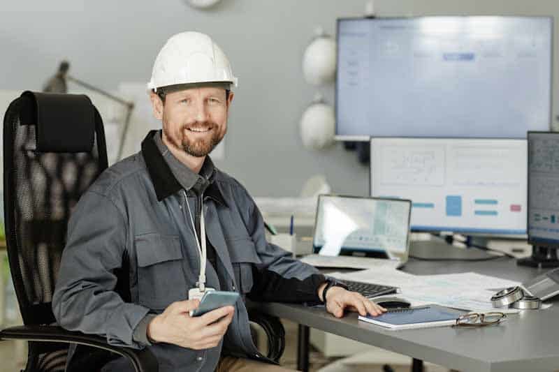 A utility service manager happily holds his smartphone, having reviewed a digital emergency response reporting form from a field technician in real-time.
