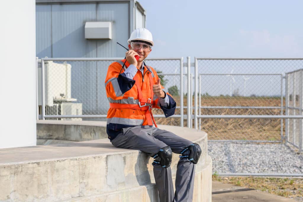 A utilities worker happily reports completion of predictive maintenance procedures at a wind farm.