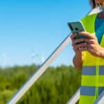 A utility worker completes predictive maintenance with digital reporting tools running on a smartphone.