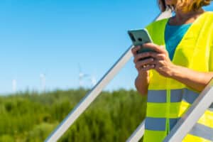 A utility worker completes predictive maintenance with digital reporting tools running on a smartphone.