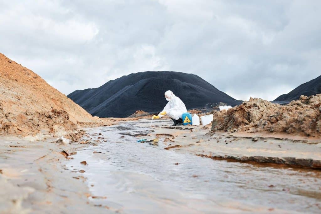 A water sample in a runoff stream is collected by a utility contamination inspector.